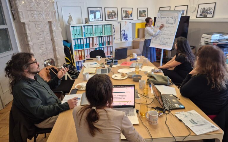 Partners of the Future Me project working around a table in Cluj-Napoca while a colleague writes on a flipchart